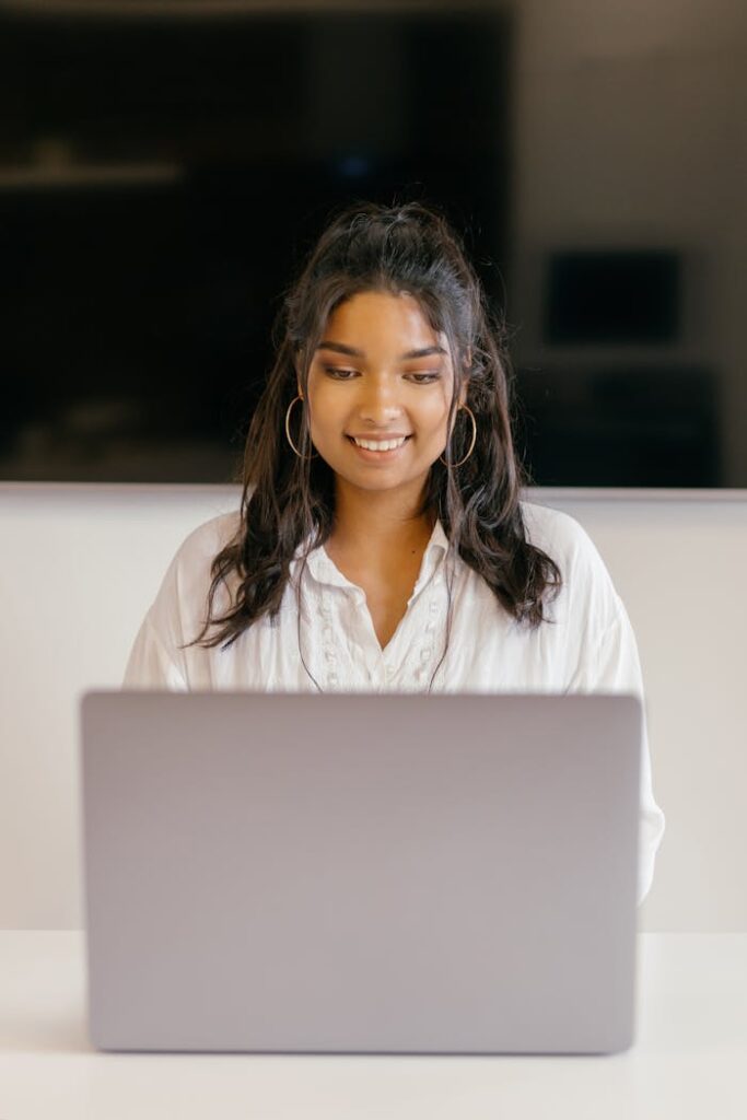 Female Student Smiling while Using a Laptop